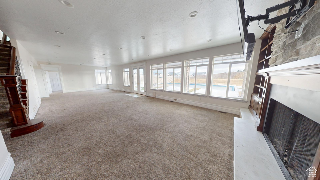 Carpeted living room with baseboards, a premium fireplace, stairway, and visible vents