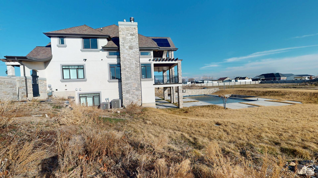 Rear view of house with a balcony, a yard, stucco siding, a chimney, and a patio area
