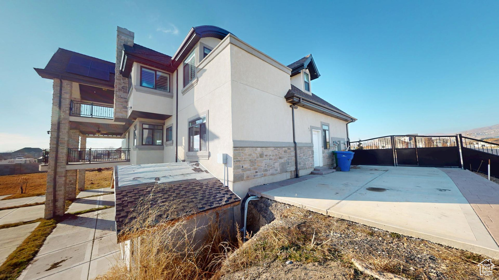 View of property exterior with stone siding, a chimney, and stucco siding
