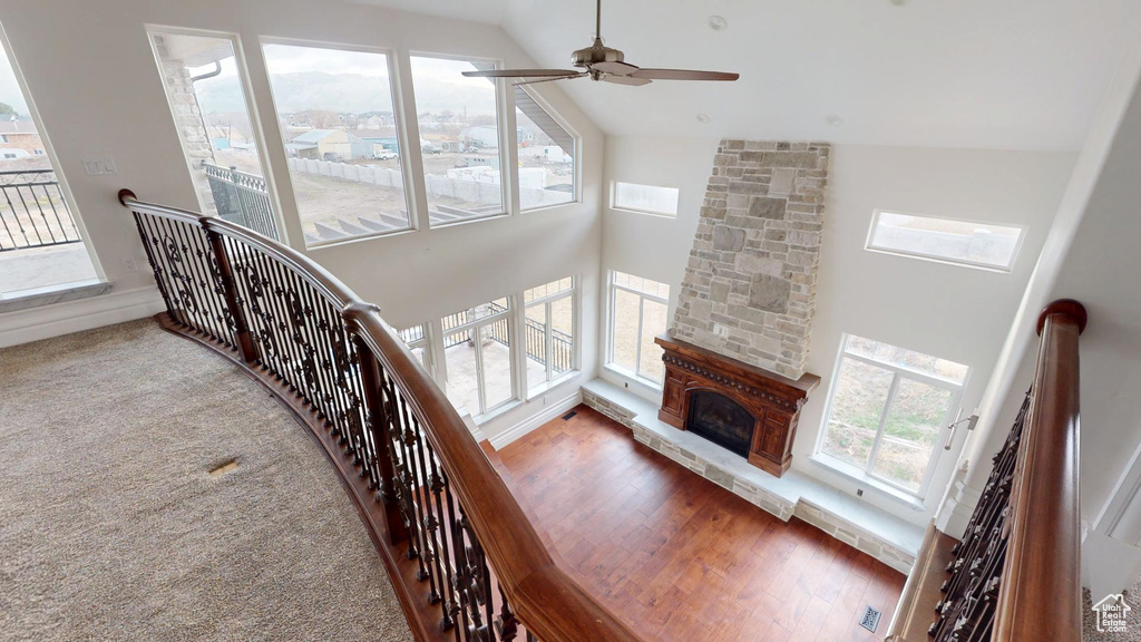 Interior space with ceiling fan, high vaulted ceiling, carpet floors, a fireplace, and wood finished floors