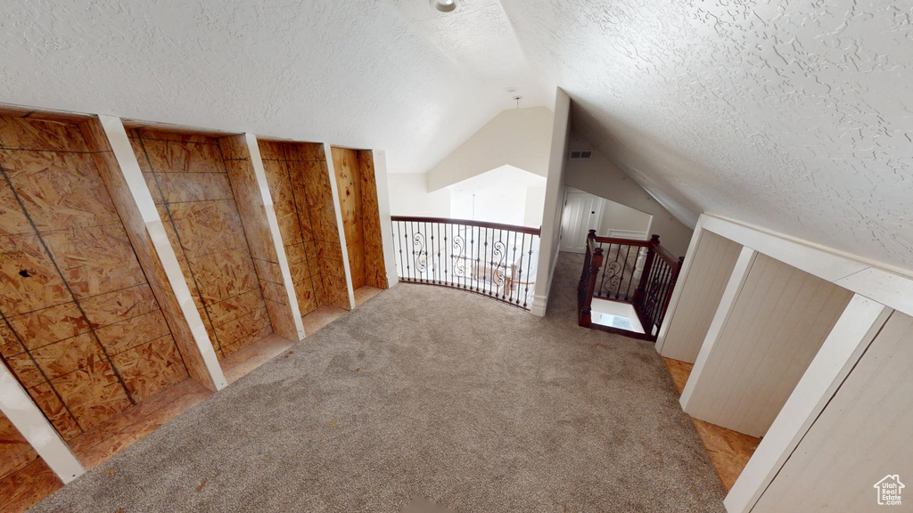 Bonus room featuring carpet, visible vents, vaulted ceiling, and a textured ceiling