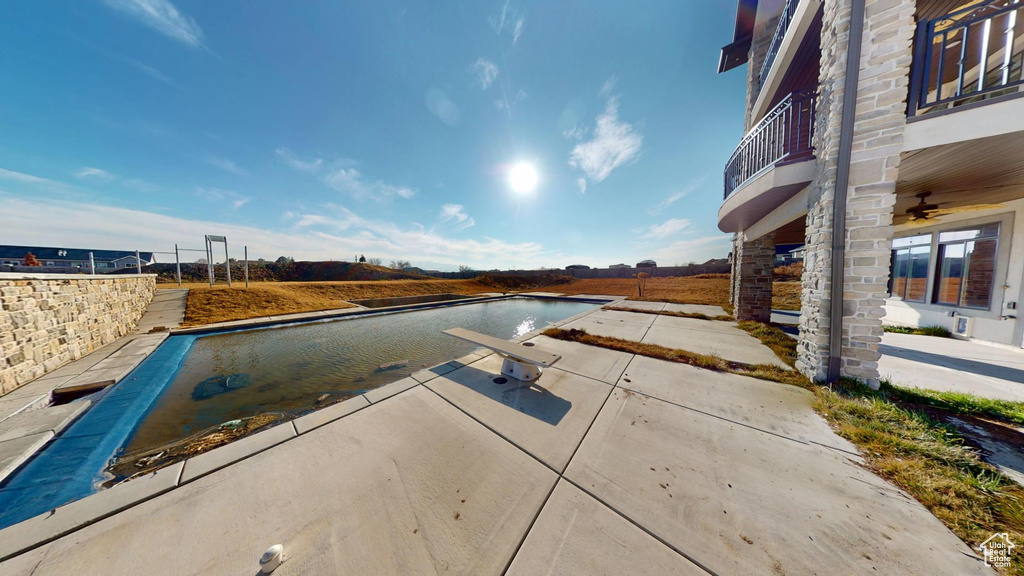 View of pool with a ceiling fan, a patio area, a covered pool, and a water view