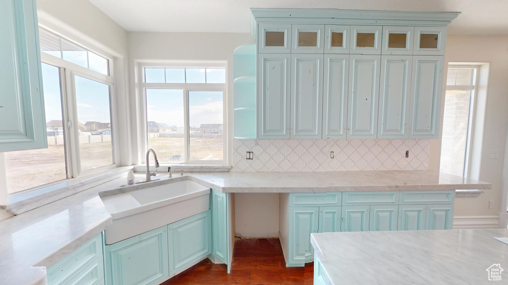 Kitchen featuring dark wood-style floors, glass insert cabinets, decorative backsplash, and a sink