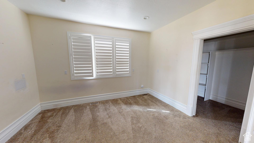 Carpeted spare room featuring baseboards