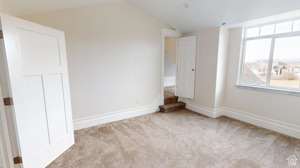 Unfurnished bedroom featuring carpet floors, baseboards, and vaulted ceiling