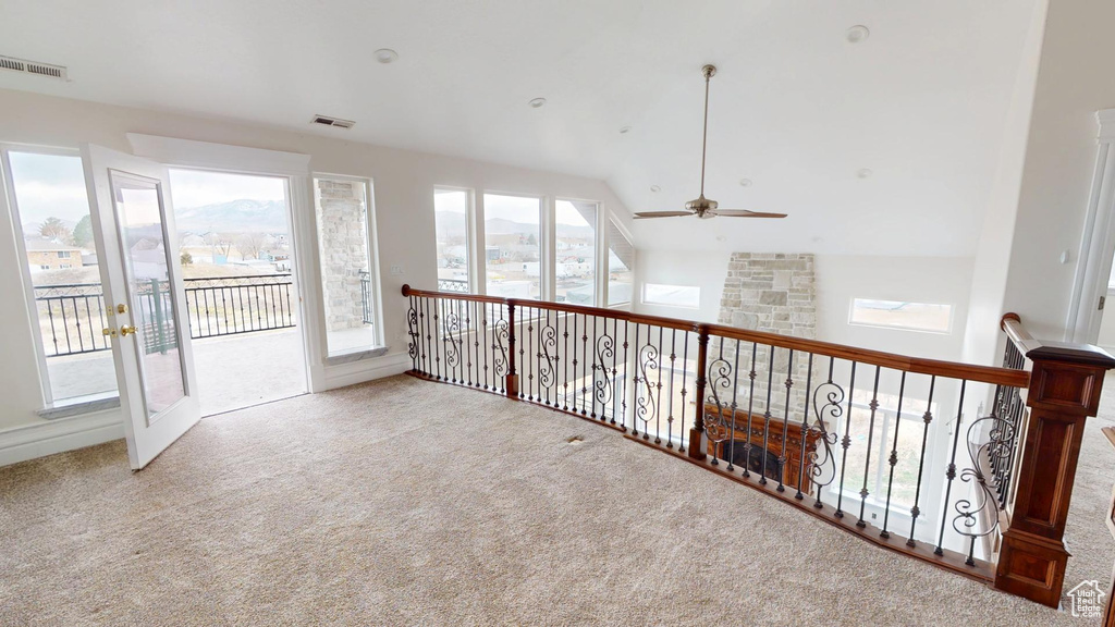 Carpeted empty room with high vaulted ceiling, plenty of natural light, and visible vents