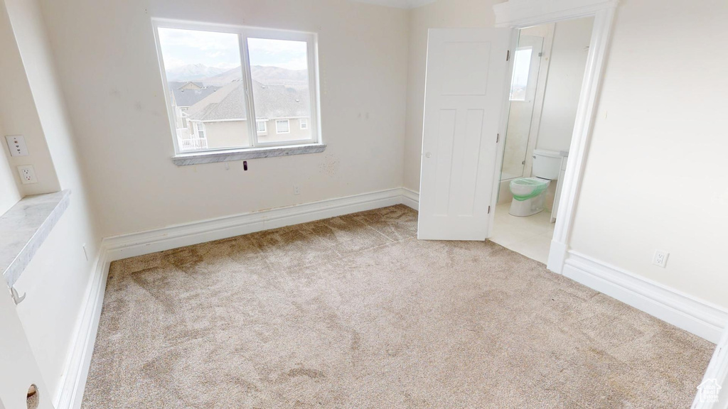 Unfurnished bedroom featuring connected bathroom and carpet flooring