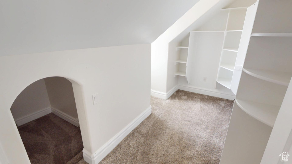 Interior space featuring lofted ceiling, built in shelves, carpet, and baseboards
