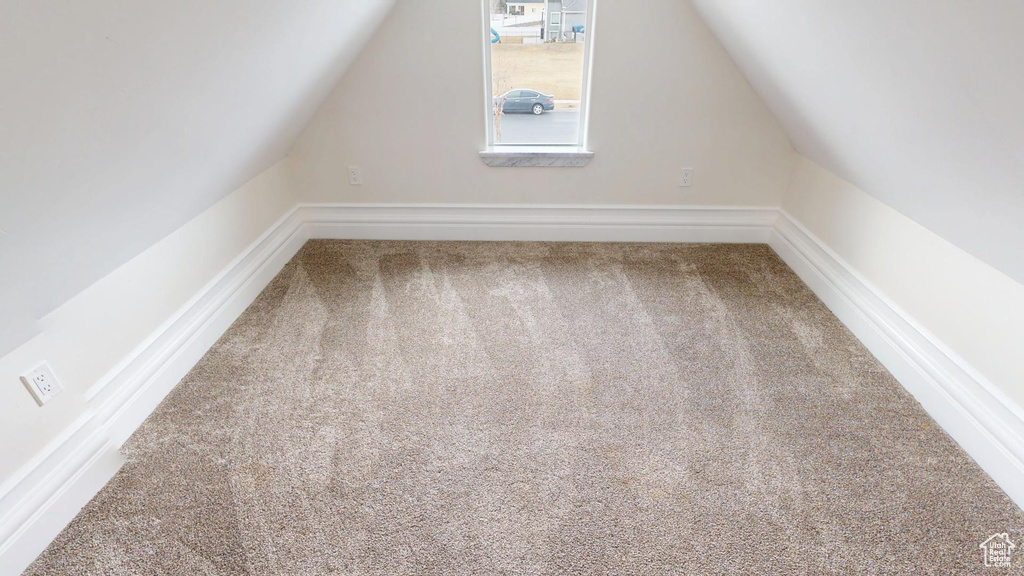 Additional living space with carpet flooring and vaulted ceiling