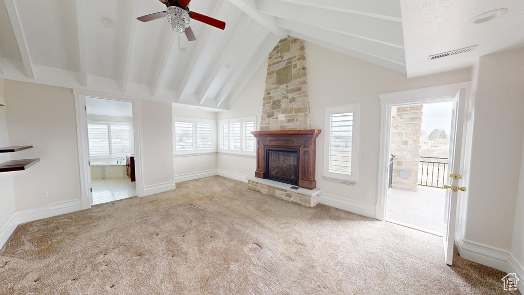 Unfurnished living room with visible vents, carpet flooring, a stone fireplace, high vaulted ceiling, and beamed ceiling