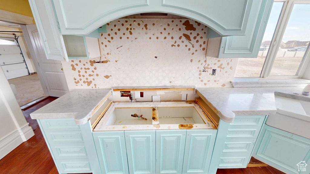 Kitchen with arched walkways, light countertops, dark wood-style flooring, and a sink