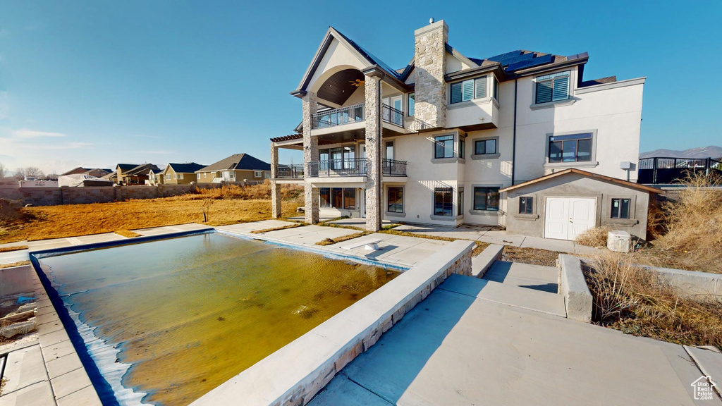 Back of property with a chimney, a balcony, and stucco siding