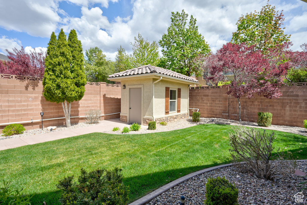 View of yard with a fenced backyard, a shed, and an outbuilding