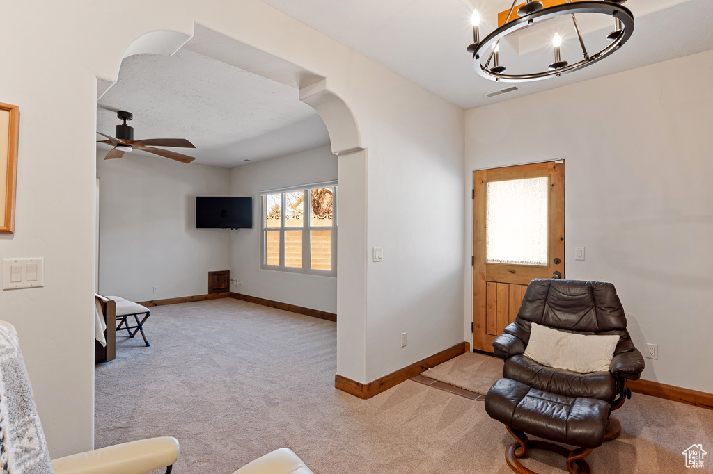 Sitting room featuring arched walkways, light colored carpet, and visible vents