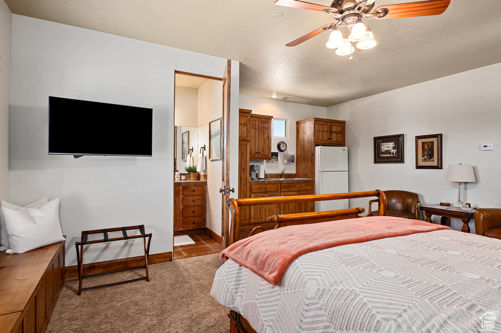 Bedroom with tile patterned flooring, a sink, baseboards, freestanding refrigerator, and carpet