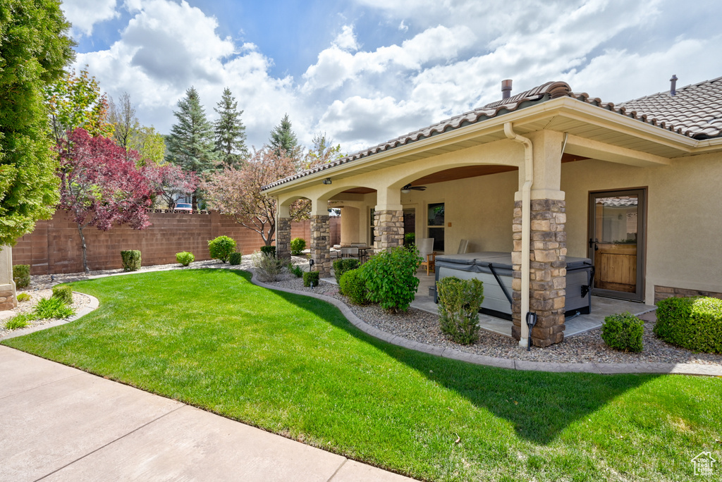 View of yard featuring a hot tub, fence, and a patio area