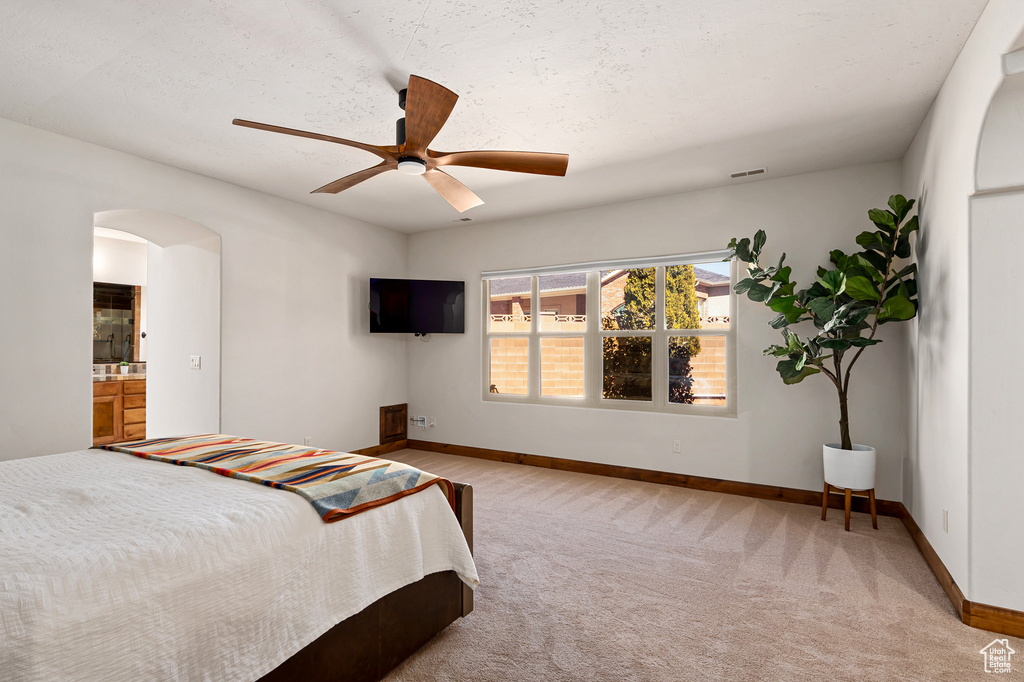 Bedroom featuring visible vents, light carpet, baseboards, ceiling fan, and arched walkways