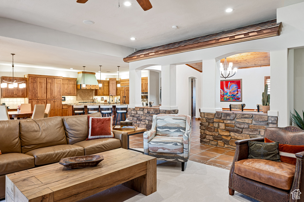Living room with arched walkways, recessed lighting, and ceiling fan with notable chandelier
