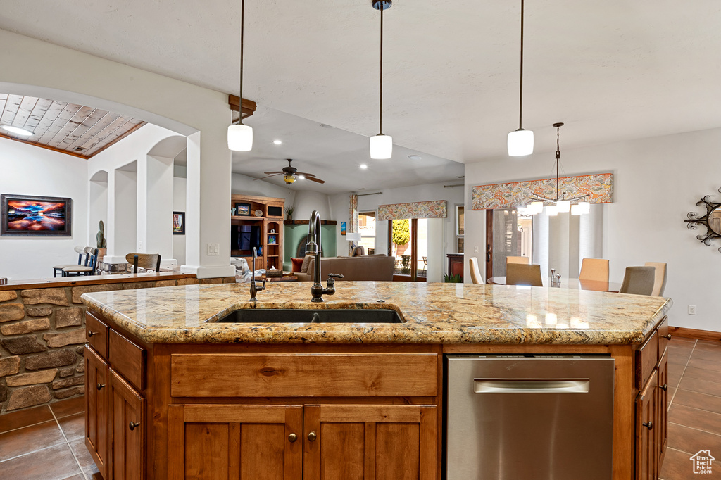 Kitchen with a sink, a kitchen island with sink, brown cabinets, and open floor plan