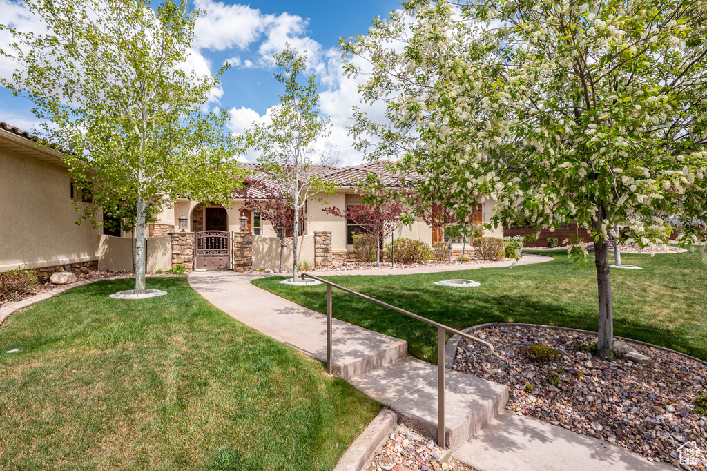 View of front of house featuring stone siding, stucco siding, a front yard, a gate, and a tiled roof