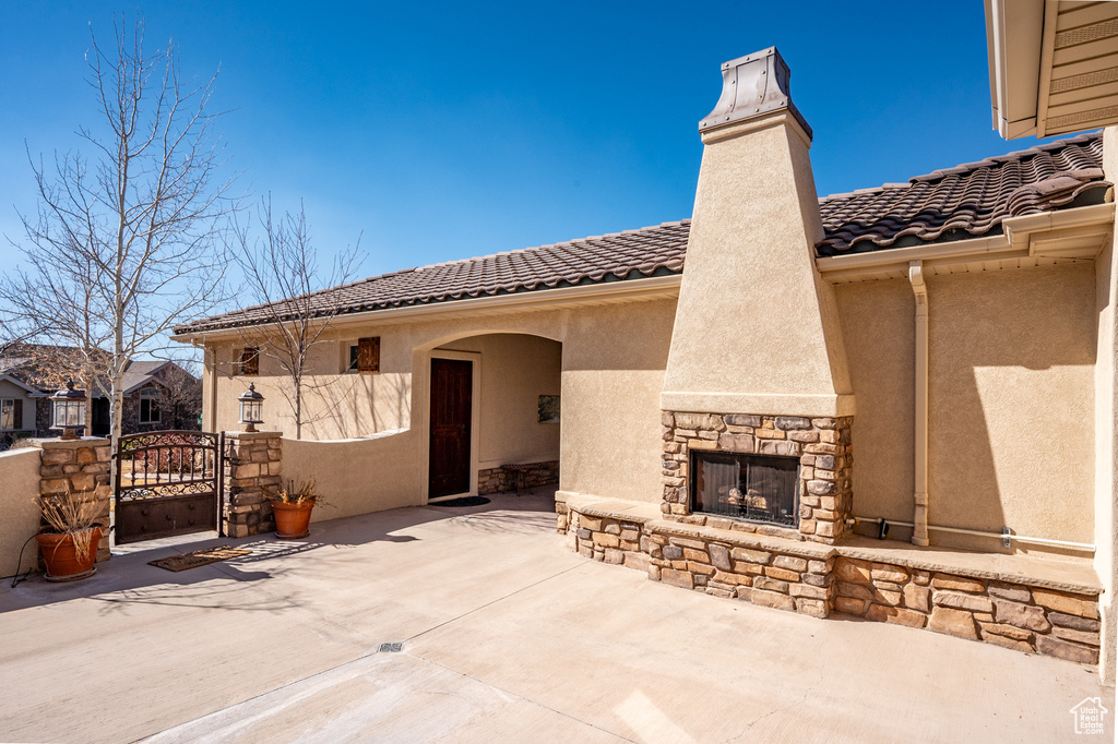 View of patio / terrace featuring an outdoor stone fireplace and a gate