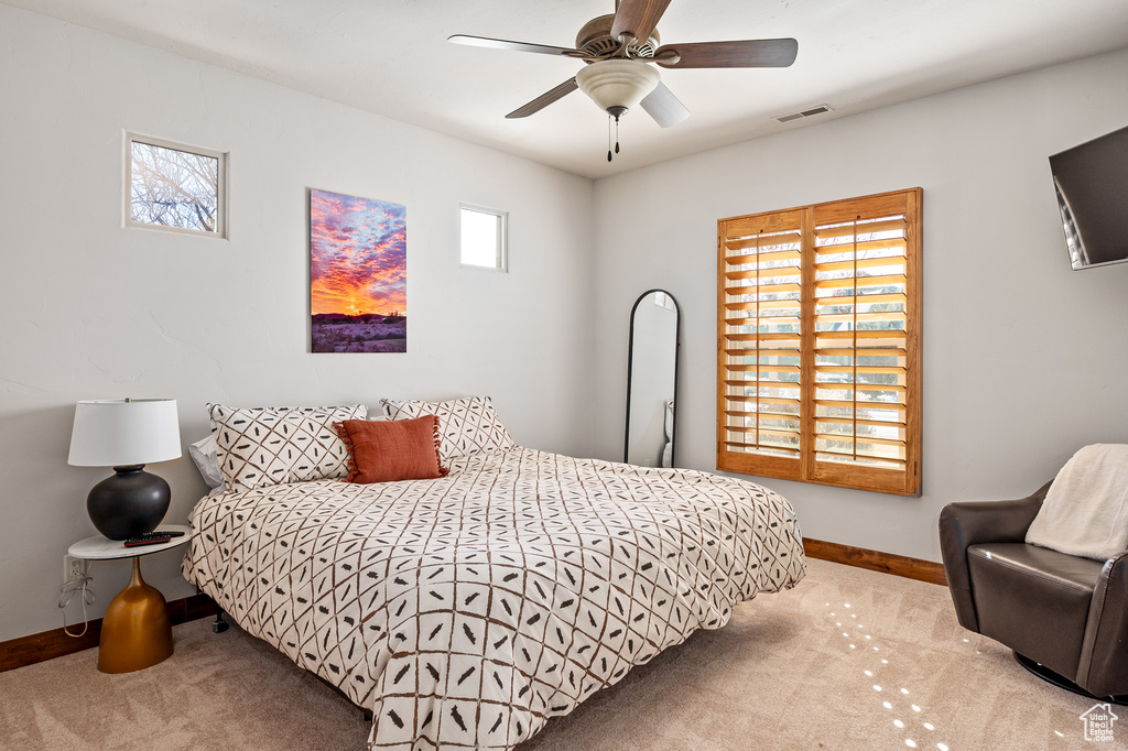 Carpeted bedroom with baseboards, a ceiling fan, and visible vents