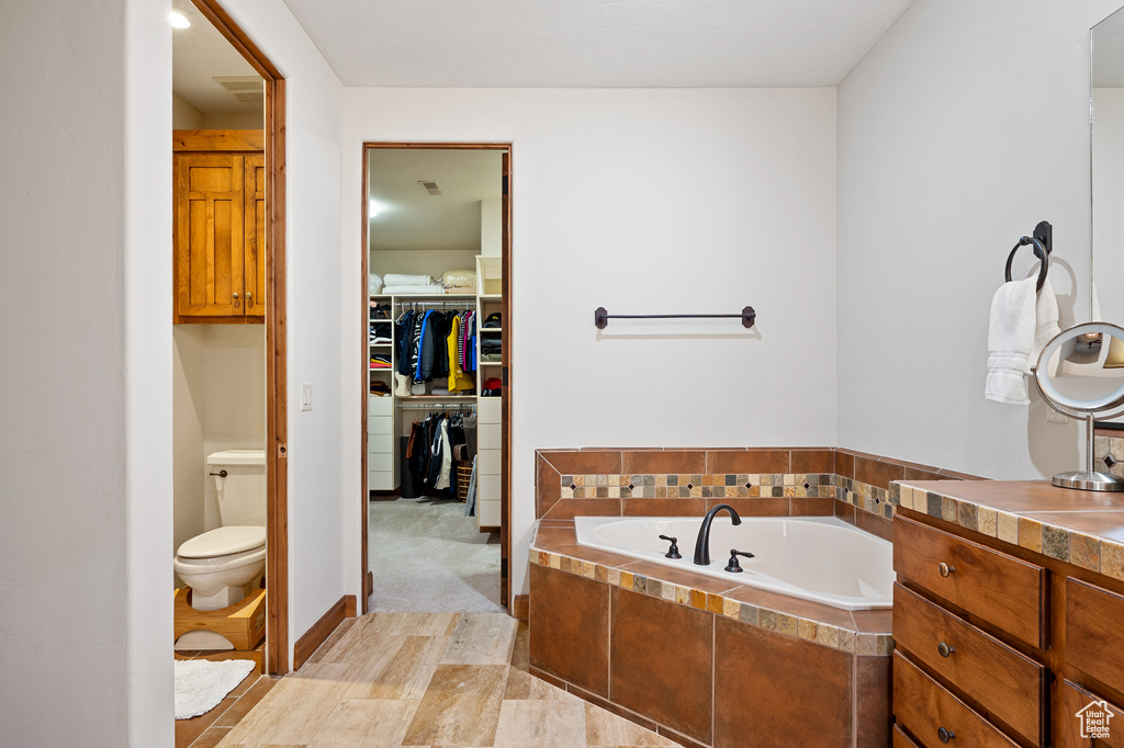Bathroom with a garden tub, toilet, and a spacious closet