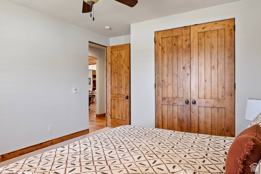 Tiled bedroom with a ceiling fan, baseboards, and a closet
