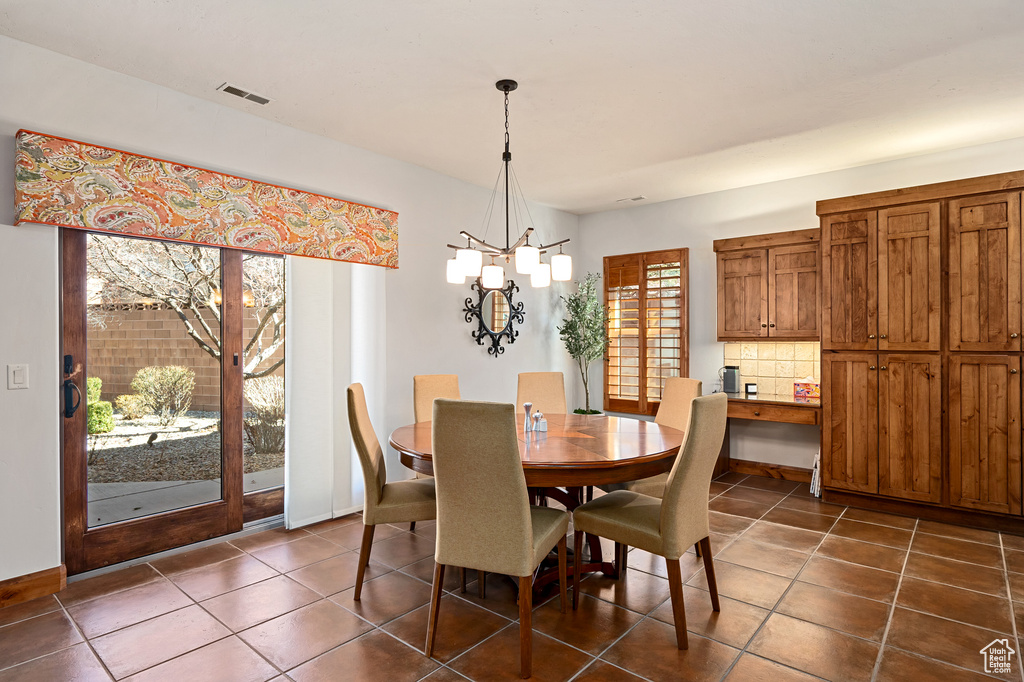 Dining room with visible vents, dark tile patterned floors, and a notable chandelier