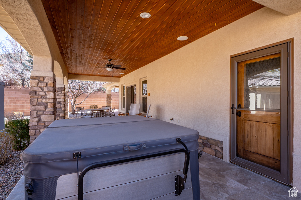 View of patio / terrace featuring fence, outdoor dining space, ceiling fan, and a hot tub