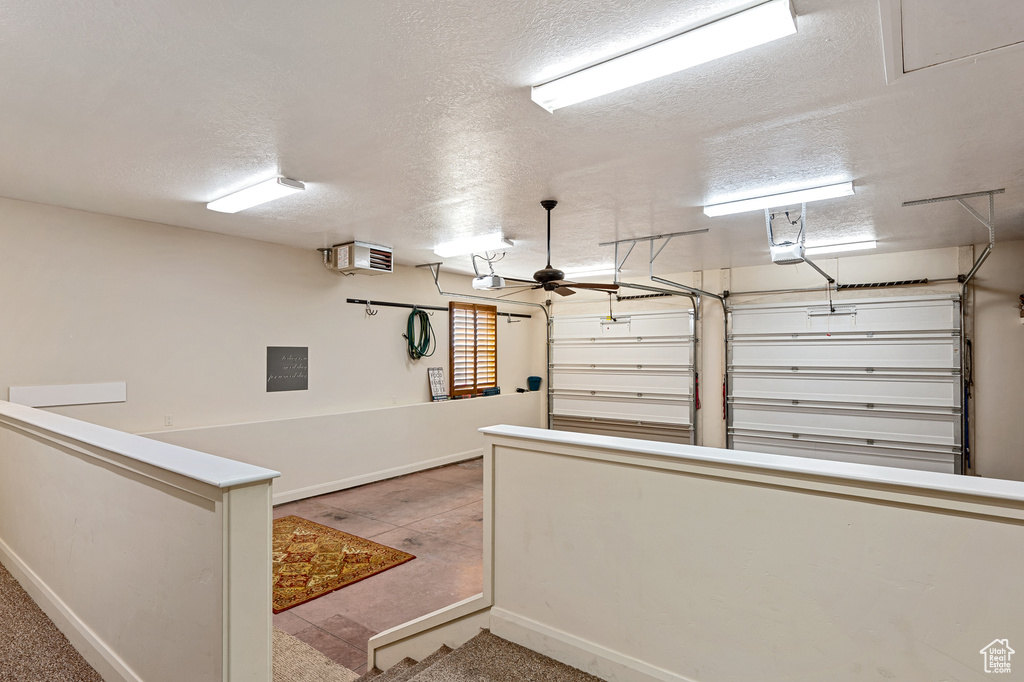 Garage featuring a ceiling fan, baseboards, and a garage door opener