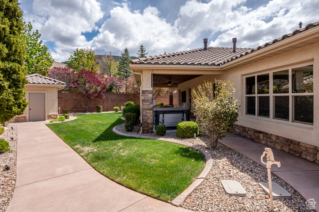 View of yard featuring fence, a patio, ceiling fan, and a hot tub