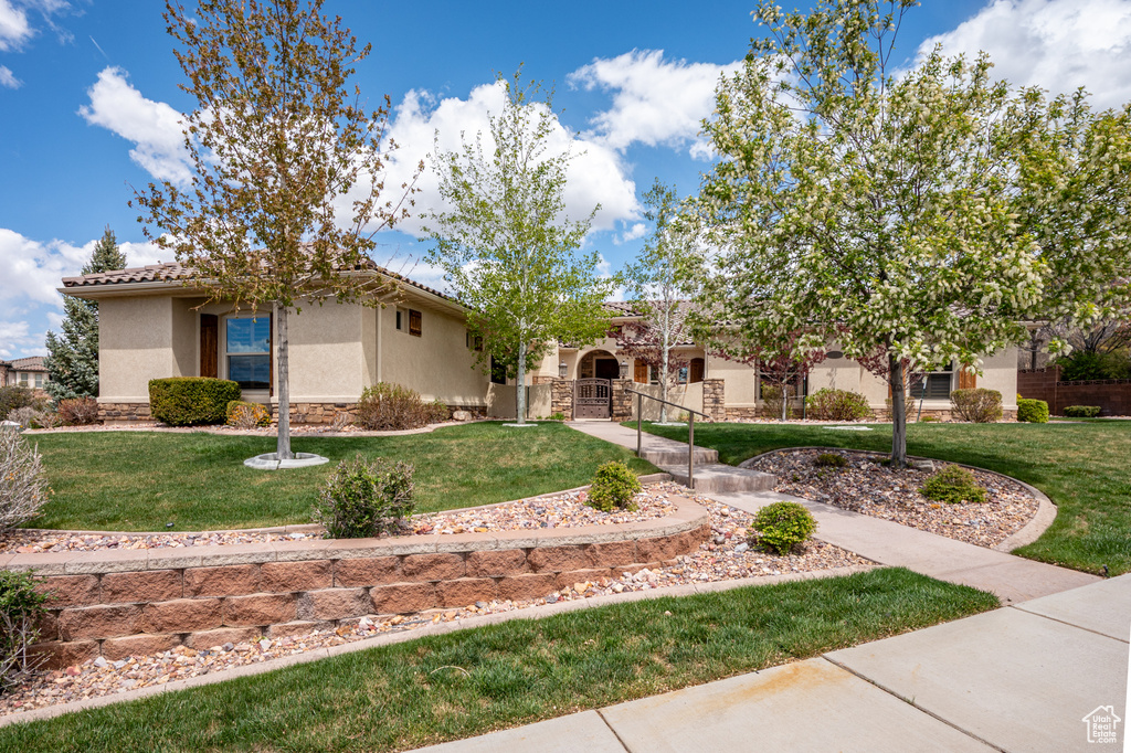 View of front of house with stone siding, stucco siding, a front yard, a gate, and a tiled roof