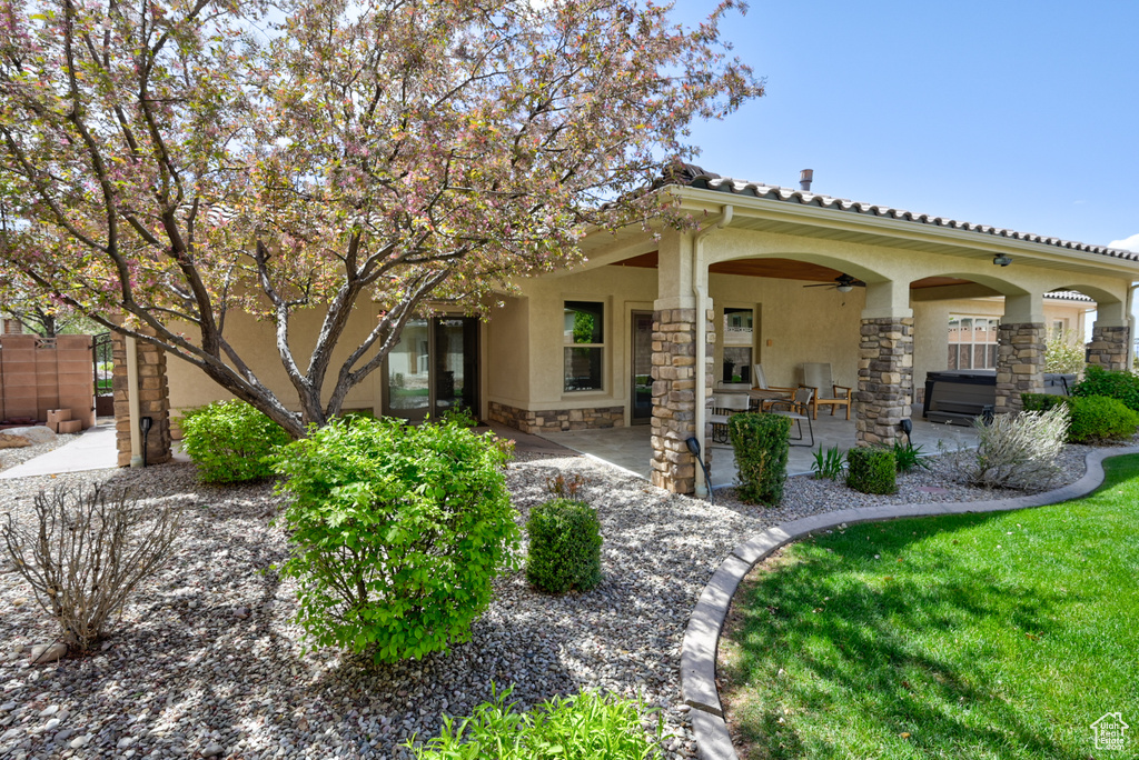 Back of property featuring a ceiling fan, a patio area, stone siding, and stucco siding