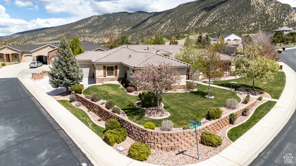 View of front of house with a tile roof, a front lawn, stucco siding, a mountain view, and driveway