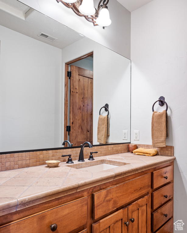Bathroom featuring vanity, tasteful backsplash, and visible vents