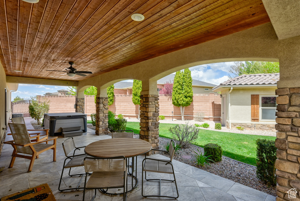 View of patio featuring a hot tub, outdoor dining area, a ceiling fan, and a fenced backyard