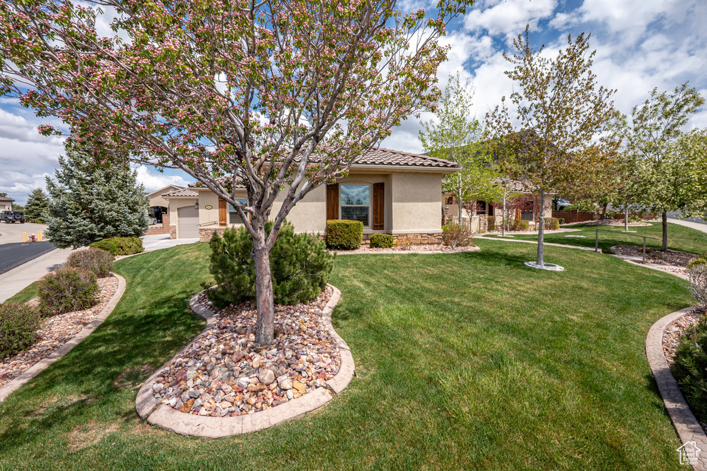 View of front of home featuring stone siding, a tile roof, a front yard, and stucco siding
