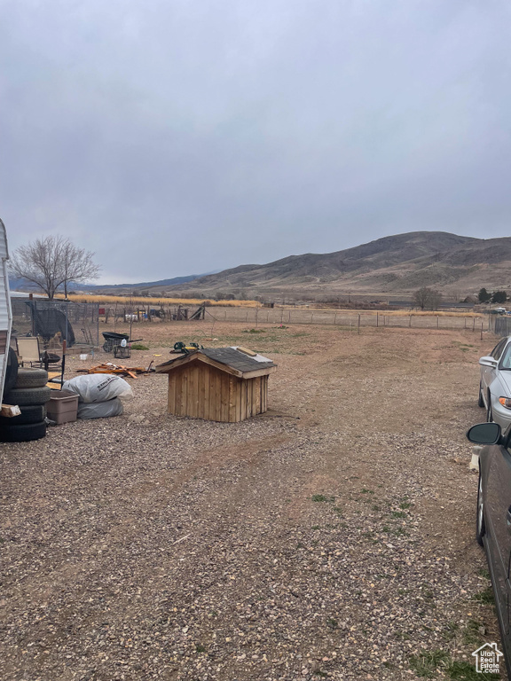 View of yard with a rural view, a mountain view, and fence