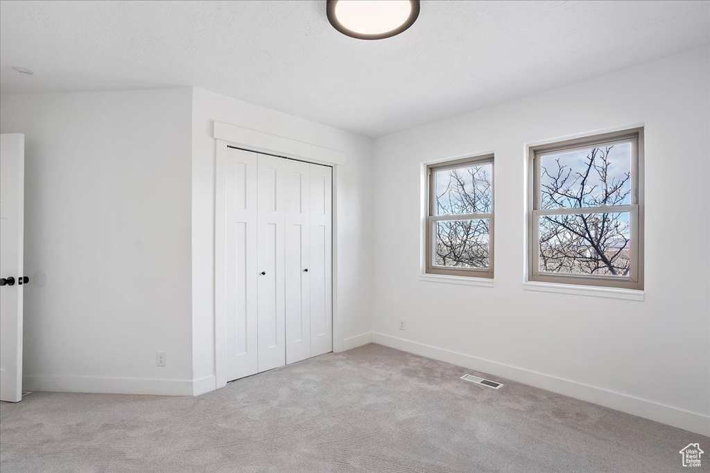 Unfurnished bedroom with carpet floors, a closet, visible vents, and baseboards
