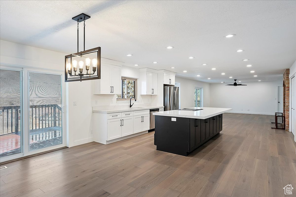 Kitchen featuring stainless steel appliances, a kitchen island, a sink, and light countertops