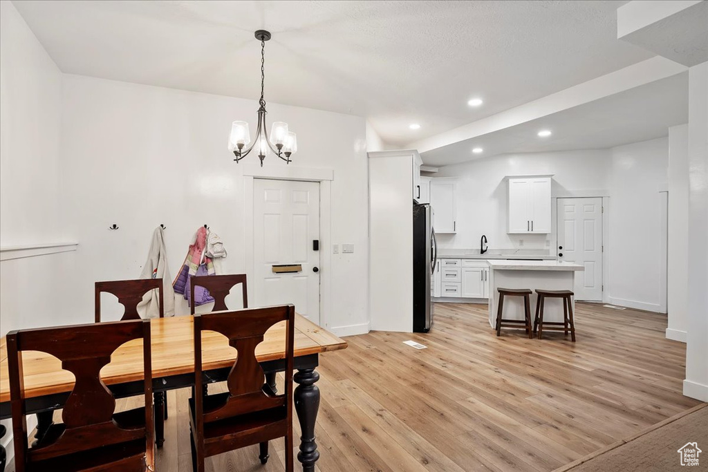 Dining room with light wood-type flooring, a notable chandelier, baseboards, and recessed lighting