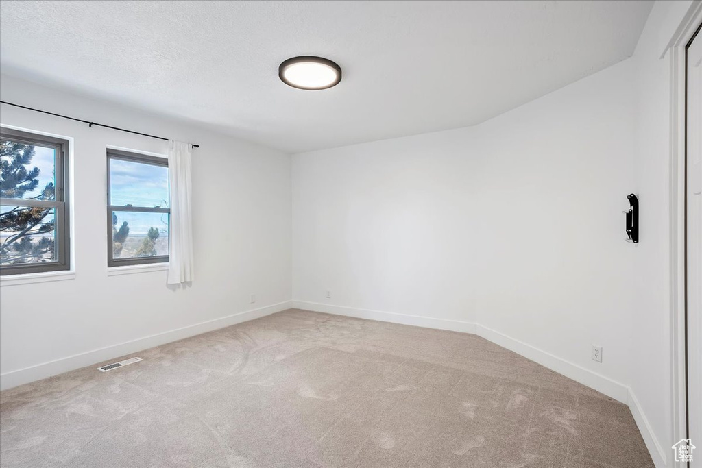 Carpeted empty room featuring baseboards and visible vents