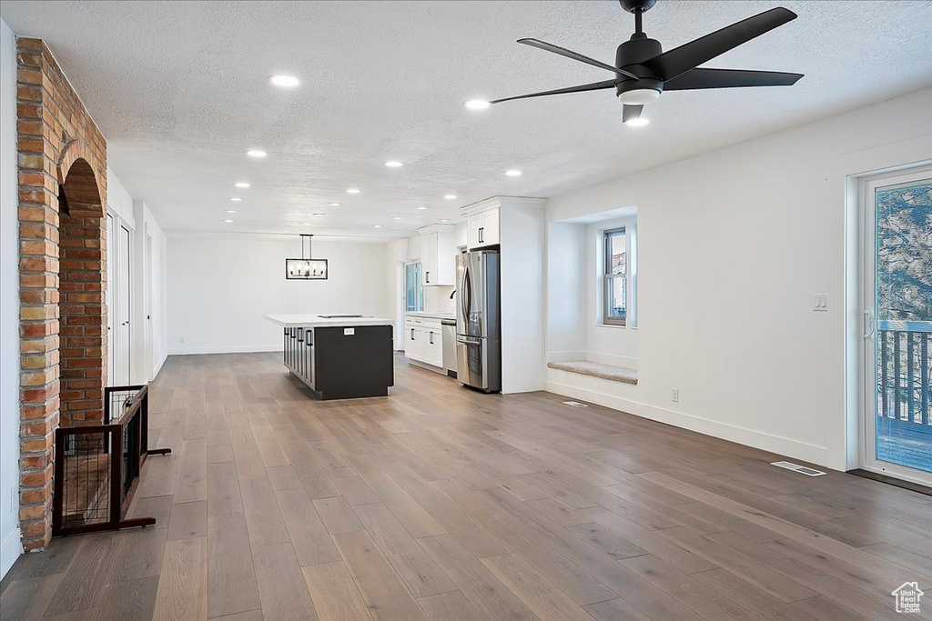 Kitchen featuring stainless steel appliances, white cabinets, dark wood-type flooring, and a kitchen island