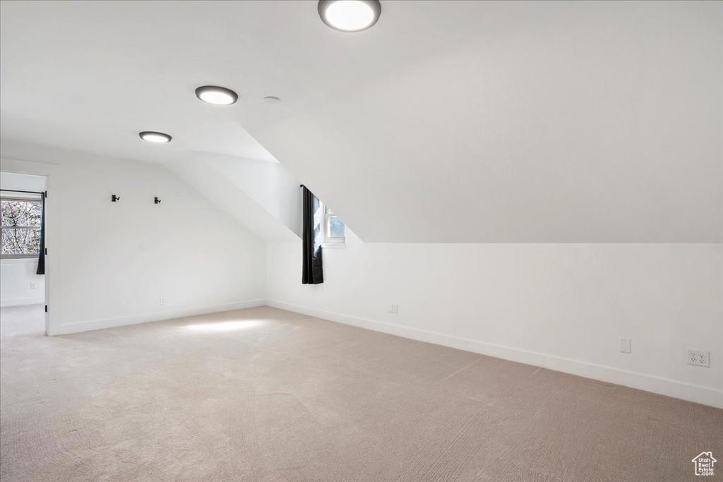 Additional living space featuring lofted ceiling, light carpet, and baseboards