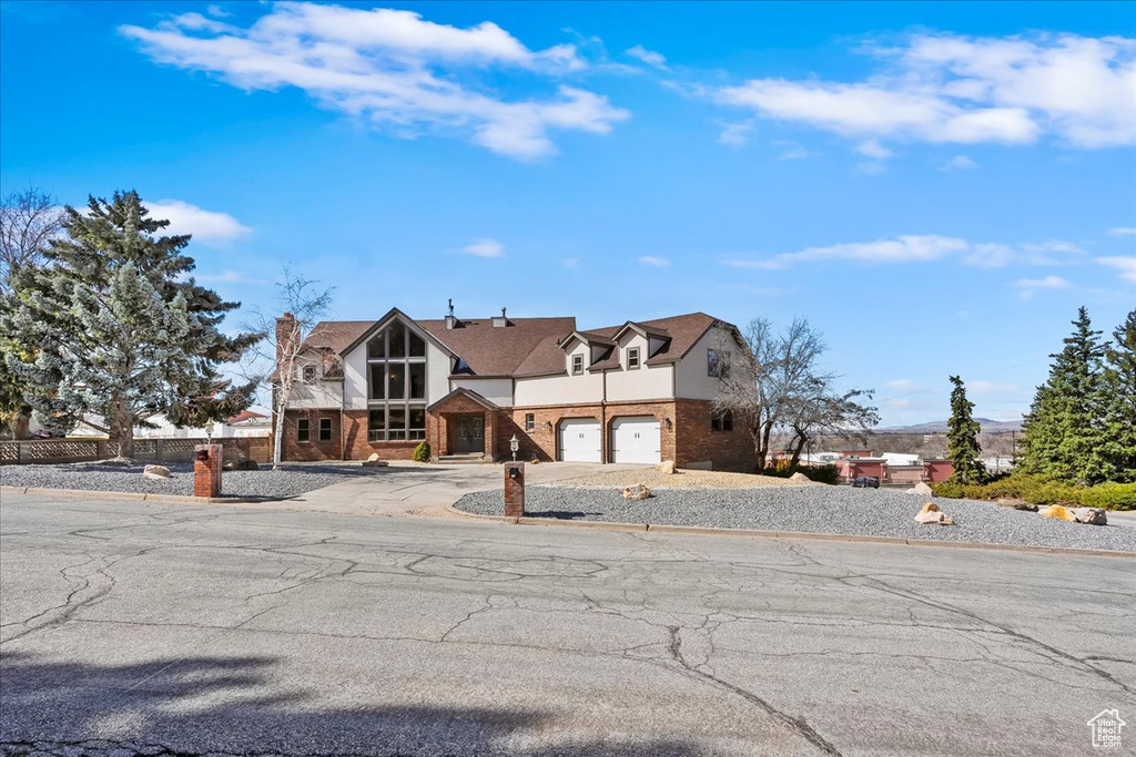 View of front facade with a garage, concrete driveway, and brick siding