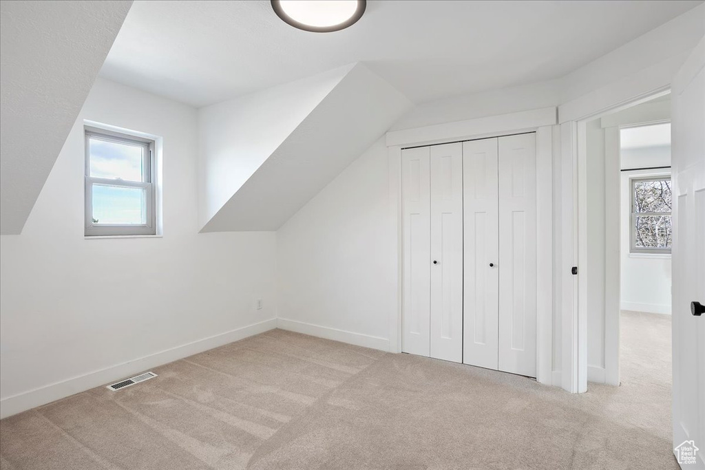 Additional living space with carpet floors, baseboards, visible vents, and lofted ceiling