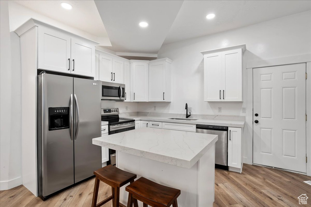 Kitchen featuring appliances with stainless steel finishes, light wood-type flooring, white cabinets, and a sink