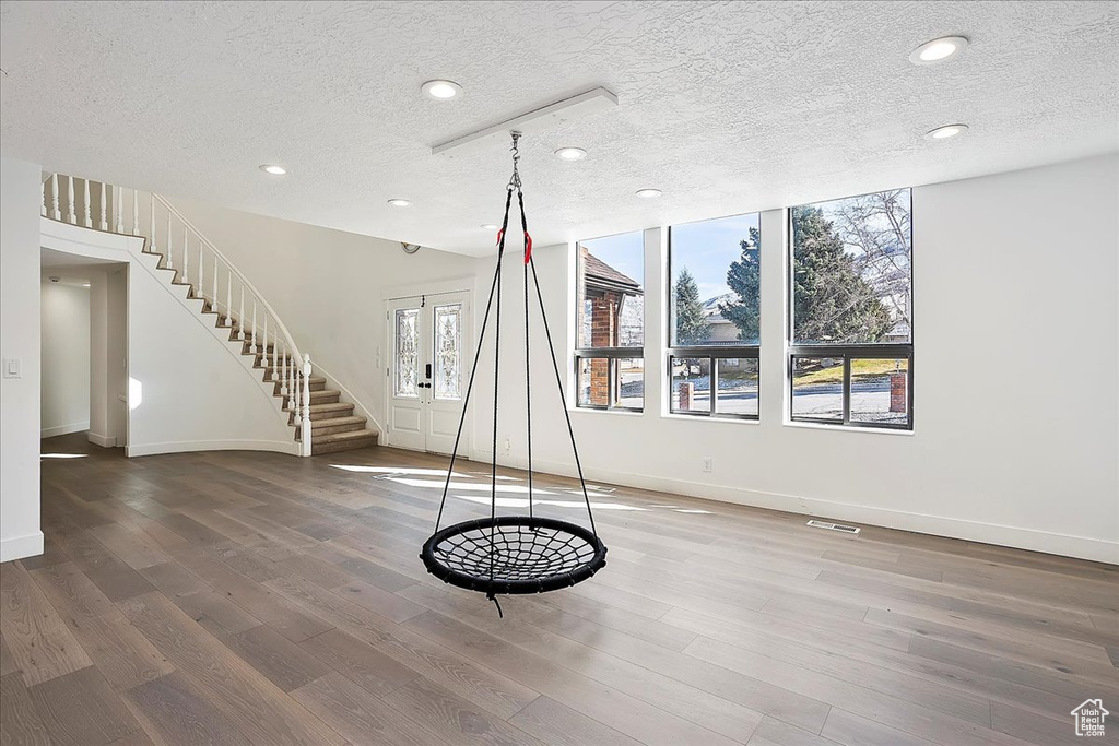 Interior space featuring french doors, visible vents, wood finished floors, baseboards, and stairs