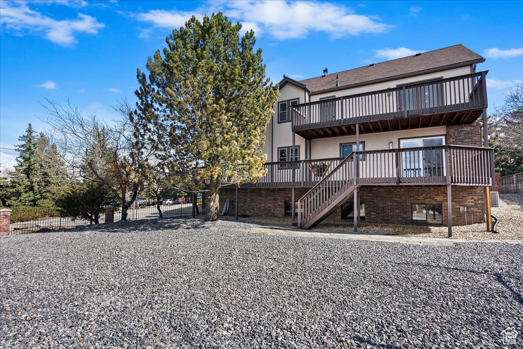 Back of property with brick siding, fence, stairway, and a balcony